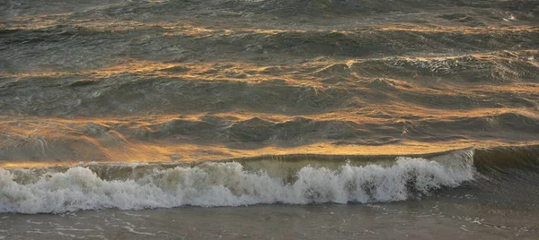 风暴过后的波罗的海海岸 夕阳西下 柔和的金色阳光 水面纹理 波纹破碎 浪花飞溅 风景如画的全景 生态概念 — 图库照片