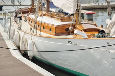 Yeni bir yat limanındaki iskeleye demirlenmiş pahalı bir retro yelkenli (ketch). Tahta meşe güvertesi, zarif detaylar. Ulaşım, denizcilik gemisi, tatiller, turizm, seyahat, yat yarışı, dinlenme