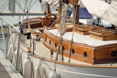 Yeni bir yat limanındaki iskeleye demirlenmiş pahalı bir retro yelkenli (ketch). Tahta meşe güvertesi, zarif detaylar. Ulaşım, denizcilik gemisi, tatiller, turizm, seyahat, yat yarışı, dinlenme