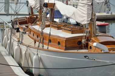 Yeni bir yat limanındaki iskeleye demirlenmiş pahalı bir retro yelkenli (ketch). Tahta meşe güvertesi, zarif detaylar. Ulaşım, denizcilik gemisi, tatiller, turizm, seyahat, yat yarışı, dinlenme
