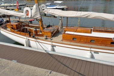 Yeni bir yat limanındaki iskeleye demirlenmiş pahalı bir retro yelkenli (ketch). Tahta meşe güvertesi, zarif detaylar. Ulaşım, denizcilik gemisi, tatiller, turizm, seyahat, yat yarışı, dinlenme
