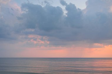 Fırtınadan sonra Baltık kıyılarından (plaj) panoramik hava manzarası. Dramatik gökyüzü, parlayan pembe günbatımı bulutları. Doğa, çevre, ekoloji, iklim değişikliği, kararsız hava. Resim gibi bir manzara.