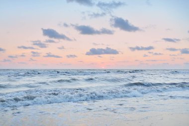 Fırtınadan sonra gün batımında Baltık Denizi. Dramatik gökyüzü, mavi ve pembe parlayan kümülüs bulutları, yumuşak altın güneş ışığı, gece yarısı güneşi. Deniz manzarası, bulut manzarası, doğa. Panoramik görünüm