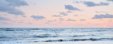 Fırtınadan sonra gün batımında Baltık Denizi. Dramatik gökyüzü, mavi ve pembe parlayan kümülüs bulutları, yumuşak altın güneş ışığı, gece yarısı güneşi. Deniz manzarası, bulut manzarası, doğa. Panoramik görünüm