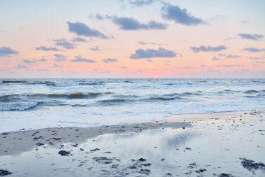 Fırtınadan sonra gün batımında Baltık Denizi. Dramatik gökyüzü, mavi ve pembe parlayan kümülüs bulutları, yumuşak altın güneş ışığı, gece yarısı güneşi. Deniz manzarası, bulut manzarası, doğa. Panoramik görünüm