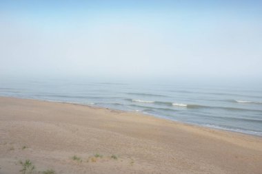 Güneşin doğuşunda sisli bir havada Baltık Denizi manzarası. Kumsal, kum tepeleri. Yumuşak güneş ışığı. Idyllic yaz deniz manzarası. Doğa, çevre, tatiller, eko-turizm, yürüyüş ve keşif kavramları