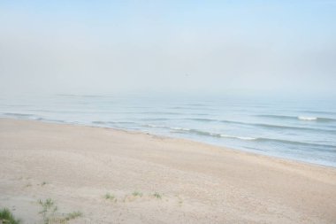 Güneşin doğuşunda sisli bir havada Baltık Denizi manzarası. Kumsal, kum tepeleri. Yumuşak güneş ışığı. Idyllic yaz deniz manzarası. Doğa, çevre, tatiller, eko-turizm, yürüyüş ve keşif kavramları