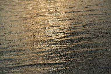 Gün batımında Baltık kıyıları (kum tepeleri). Açık mavi gökyüzü ve altın güneş ışığı, durgun sulardaki yansımalar. Soyut doğal desen, doku, arkaplan, deniz manzarası, konsept görüntü, grafik kaynaklar