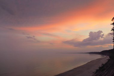 Fırtınadan sonra Baltık kıyılarından panoramik hava manzarası. Kum tepeleri. Dramatik gökyüzü, parlak pembe ve altın bulutlar. Doğa, çevre, eko-turizm, yaz tatilleri. Idyllic rüya gibi deniz manzarası
