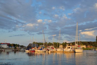 Şık ve modern yelkenliler ve kesiciler gün batımında yat limanında bir rıhtıma demirlediler. Tatiller, ulaşım, spor, eğlence, turizm, seyahat, liman