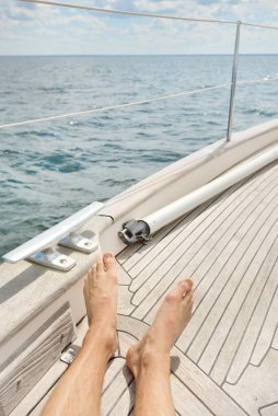 Yelkenlide takılan bir adam, tahta meşe güvertesi, açık deniz. Eski pahalı klasik yat. Özgürlük, seyahat tutkusu, eğlence aktivitesi, spor, yelkencilik, gezi, tatil, yaz tatili.