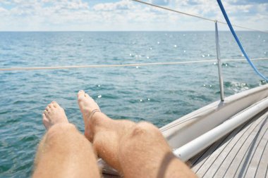 Yelkenlide takılan bir adam, tahta meşe güvertesi, açık deniz. Eski pahalı klasik yat. Özgürlük, seyahat tutkusu, eğlence aktivitesi, spor, yelkencilik, gezi, tatil, yaz tatili.