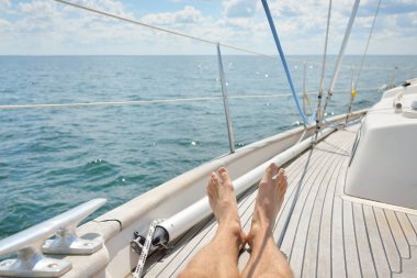 Yelkenlide takılan bir adam, tahta meşe güvertesi, açık deniz. Eski pahalı klasik yat. Özgürlük, seyahat tutkusu, eğlence aktivitesi, spor, yelkencilik, gezi, tatil, yaz tatili.