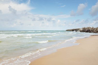 Fırtınadan sonra Baltık kıyıları (kum tepeleri, plaj). Dramatik gökyüzü, parlayan bulutlar. Deniz fenerine doğru ilerleyin, dalgalar yakın çekim yapsın. Doğa, çevre, ekoloji, eko-turizm, yürüyüş, keşif teması