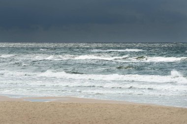 Fırtınadan sonra Baltık kıyıları (kum tepeleri, plaj). Dramatik gökyüzü, parlayan bulutlar. Resimli panoramik manzara. Doğa, çevre, ekoloji, eko-turizm, yürüyüş, keşif kavramları