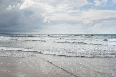 Fırtınadan sonra Baltık kıyıları (kum tepeleri, plaj). Dramatik gökyüzü, parlayan bulutlar. Resimli panoramik manzara. Doğa, çevre, ekoloji, eko-turizm, yürüyüş, keşif kavramları