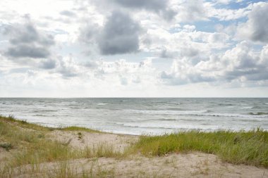 Fırtınadan sonra Baltık kıyıları (kum tepeleri, plaj). Dramatik gökyüzü, parlayan bulutlar. Resimli panoramik manzara. Doğa, çevre, ekoloji, eko-turizm, yürüyüş, keşif kavramları