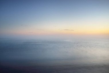 Kalın beyaz sis bulutları içinde nefes kesici panoramik deniz manzarası. Parlak gökyüzü, gece yarısı güneşi, alacakaranlık. Resimli bir manzara var. Rüya gibi bir manzara. Saf doğa, çevre, ekoloji, turizm