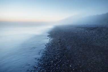 Baltık deniz kıyısının sisli manzarası nefes kesici panoramik. Parlak gökyüzü, gece yarısı güneşi, alacakaranlık. Resimli bir manzara var. Rüya gibi bir manzara. Saf doğa, çevre, ekoloji, turizm