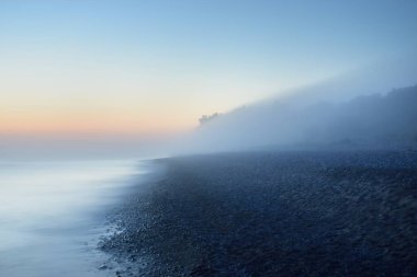 Baltık deniz kıyısının sisli manzarası nefes kesici panoramik. Parlak gökyüzü, gece yarısı güneşi, alacakaranlık. Resimli bir manzara var. Rüya gibi bir manzara. Saf doğa, çevre, ekoloji, turizm