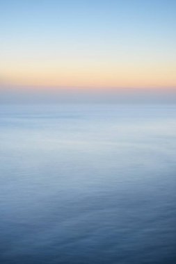 Kalın beyaz sis bulutları içinde nefes kesici panoramik deniz manzarası. Parlak gökyüzü, gece yarısı güneşi, alacakaranlık. Resimli bir manzara var. Rüya gibi bir manzara. Saf doğa, çevre, ekoloji, turizm