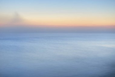 Kalın beyaz sis bulutları içinde nefes kesici panoramik deniz manzarası. Parlak gökyüzü, gece yarısı güneşi, alacakaranlık. Resimli bir manzara var. Rüya gibi bir manzara. Saf doğa, çevre, ekoloji, turizm