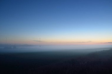 Gün batımında sisli bir arazide (orman çimenliği, çayır). Ayın doğuşu, alacakaranlık, karamsar gökyüzü. Idyllic yaz kırsal manzarası. Doğa, çevre, ekoloji, sessizlik, yalnızlık kavramları