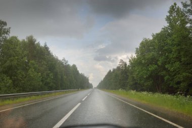Bir yaz günü ormanda boş bir otoyol (asfalt yol). Dramatik fırtına bulutları, yağmur. Turizm, yolculuk, özgürlük, tatiller, lojistik, ücra yerler kavramları. Arabadan bak.