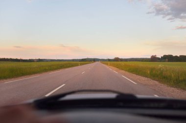 Gün batımında tarla ve orman boyunca (yeni asfalt yol) boş bir otoyoldur. Yağmurdan sonra dramatik bir şekilde parlayan bulutlar. Turizm, yol gezisi, özgürlük, tatiller, lojistik, uzak yerler kavramları