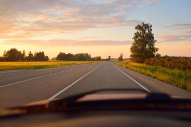 Gün batımında tarla ve orman boyunca (yeni asfalt yol) boş bir otoyoldur. Yağmurdan sonra dramatik bir şekilde parlayan bulutlar. Turizm, yol gezisi, özgürlük, tatiller, lojistik, uzak yerler kavramları