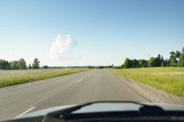 Tarımsal alan ve ormanın içinden geçen ülke otoyolu. Fırtınadan sonra dramatik bir gökyüzü. Yazın kırsal alanda. Yumuşak güneş ışığı. Tatiller, yol gezisi, sürüş, yolculuk