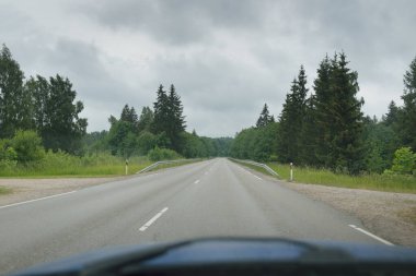 Bir yaz günü tarla ve orman boyunca (asfalt yol) bomboş bir otoyol. Dramatik fırtına bulutları, yağmur. Turizm, yolculuk, özgürlük, tatiller, lojistik, ücra yerler kavramları. Arabadan bak.