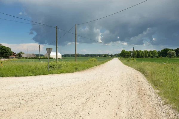 Fırtınadan sonra tarladan geçen boş köy yolu. Arabadan bir manzara. Idyllic kırsal kesim. Renkli, parlayan günbatımı bulutları. Ulaşım, yolculuk, özgürlük, seyahat tutkusu, uzak yerler kavramları.