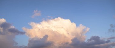 Gün batımında parlak pembe ve altın kümülüs bulutlarıyla açık mavi gökyüzü. Dramatik bulut manzarası. Sanat, meteoroloji, cennet, umut, barış, grafik kaynakları, resimli panoramik manzara