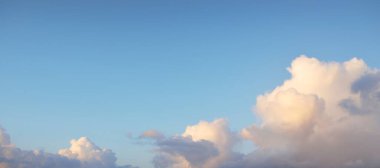 Gün batımında parlak pembe ve altın kümülüs bulutlarıyla açık mavi gökyüzü. Dramatik bulut manzarası. Sanat, meteoroloji, cennet, umut, barış, grafik kaynakları, resimli panoramik manzara