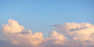 Gün batımında parlak pembe ve altın kümülüs bulutlarıyla açık mavi gökyüzü. Dramatik bulut manzarası. Sanat, meteoroloji, cennet, umut, barış, grafik kaynakları, resimli panoramik manzara