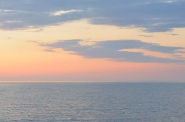 Gün batımında Baltık Denizi. Dramatik gökyüzü, mavi ve pembe parlayan bulutlar, yumuşak altın güneş ışığı, gece yarısı güneşi. Deniz manzarası, bulut manzarası, doğa. Panoramik görünüm