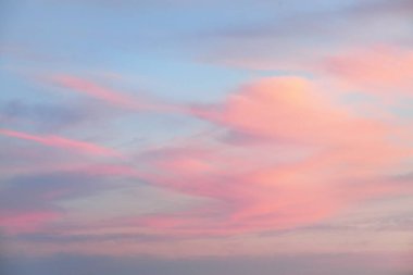 Açık mavi gökyüzü. Pembe parlayan, altın sirrus ve kümülüs bulutları fırtına üstüne, yumuşak güneş ışığı. Gün batımı bulutları. Meteoroloji, gece yarısı güneşi, cennet, huzur, grafik kaynakları, resimli panoramik manzara