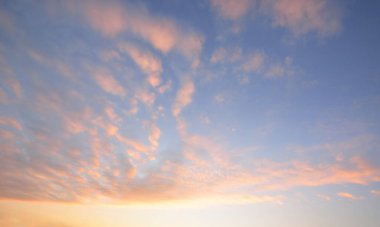 Açık mavi gökyüzü, pembe ve altın rengi sirrus ve günbatımında fırtına üstüne kümülüs bulutları. Dramatik bulut manzarası. Sanat, meteoroloji, cennet, umut, barış, grafik kaynakları, resimli panoramik manzara