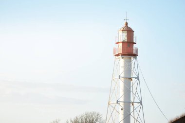 Deniz fenerine karşı açık mavi gün batımı gökyüzü. Hafif ışık, altın saat. Letonya 'nın Pape köyü. Idyllic manzara. İnşaat, sahil güvenlik, yön bulma, umut ve barışın sembolü. Panoramik görünüm, boşluğu kopyala