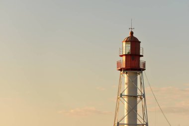 Deniz fenerine karşı açık mavi gün batımı gökyüzü. Hafif ışık, altın saat. Letonya 'nın Pape köyü. Idyllic manzara. İnşaat, sahil güvenlik, yön bulma, umut ve barışın sembolü. Panoramik görünüm, boşluğu kopyala
