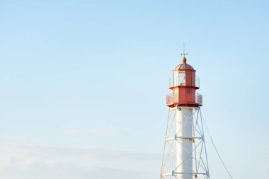 Deniz fenerine karşı açık mavi gün batımı gökyüzü. Hafif ışık, altın saat. Letonya 'nın Pape köyü. Idyllic manzara. İnşaat, sahil güvenlik, yön bulma, umut ve barışın sembolü. Panoramik görünüm, boşluğu kopyala