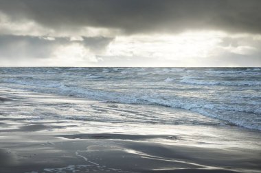 Kumlu bir sahilden (kum tepeleri) Baltık denizinin panoramik görüntüsü. Koyu bulutlu dramatik bir gökyüzü. Dalgalar, su sıçramaları. Idyllic deniz manzarası. Sıcak kış havası, iklim değişikliği, doğa. Danimarka