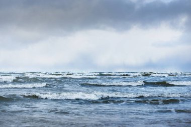 Kumlu bir sahilden (kum tepeleri) Baltık denizinin panoramik görüntüsü. Koyu bulutlu dramatik bir gökyüzü. Dalgalar, su sıçramaları. Idyllic deniz manzarası. Sıcak kış havası, iklim değişikliği, doğa. Danimarka