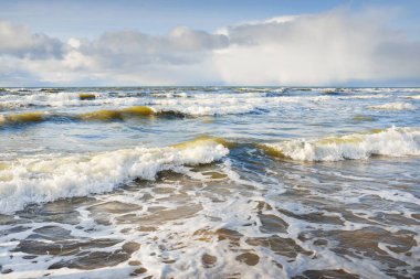 Kumlu sahilden Baltık denizinin panoramik görüntüsü (kum tepeleri). Parlayan bulutları, güneş ışınları olan dramatik bir gökyüzü. Dalgalar, su sıçramaları. Idyllic deniz manzarası. Sıcak kış havası, iklim değişikliği, doğa. Danimarka