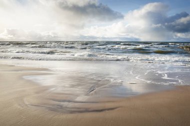 Kumlu sahilden Baltık denizinin panoramik görüntüsü (kum tepeleri). Parlayan bulutları, güneş ışınları olan dramatik bir gökyüzü. Dalgalar, su sıçramaları. Idyllic deniz manzarası. Sıcak kış havası, iklim değişikliği, doğa. Danimarka