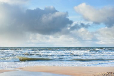Kumlu sahilden Baltık denizinin panoramik görüntüsü (kum tepeleri). Parlayan bulutları, güneş ışınları olan dramatik bir gökyüzü. Dalgalar, su sıçramaları. Idyllic deniz manzarası. Sıcak kış havası, iklim değişikliği, doğa. Danimarka