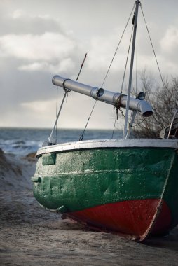 Baltık Denizi 'nin kumlu kıyılarında küçük bir köyde karada duran eski yeşil balıkçı teknesi. Jurmalciems, Letonya. Gemi, ulaşım, lojistik, endüstri, balıkçılık, çiftlik, gıda üretimi. Kırsal alan
