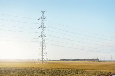 Elektrik hattı açık mavi gökyüzüne karşı, yakın plan. Şehir manzarası kavramı. Enerji, enerji üretimi, özel ekipman, endüstri, çevresel hasar, ekoloji, altyapı, ormanların tahrip