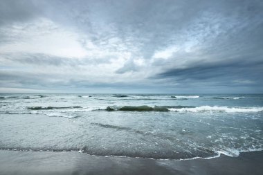 Kumlu bir sahilden (kum tepeleri) Baltık denizinin panoramik görüntüsü. Parlayan bulutlar, dalgalar ve su sıçramalarıyla dramatik bir gökyüzü. Idyllic deniz manzarası. Sıcak kış havası, iklim değişikliği, doğa. Danimarka